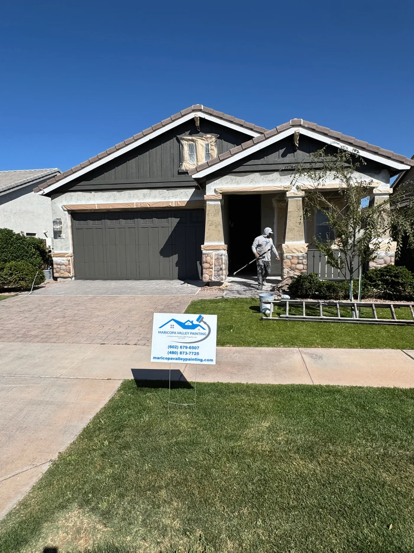 Maricopa Valley Painting crew repainting a craftsman-style home with a company yard sign out front