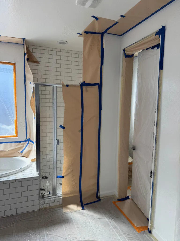 Bathroom with tile, window, and fixtures fully masked before interior painting