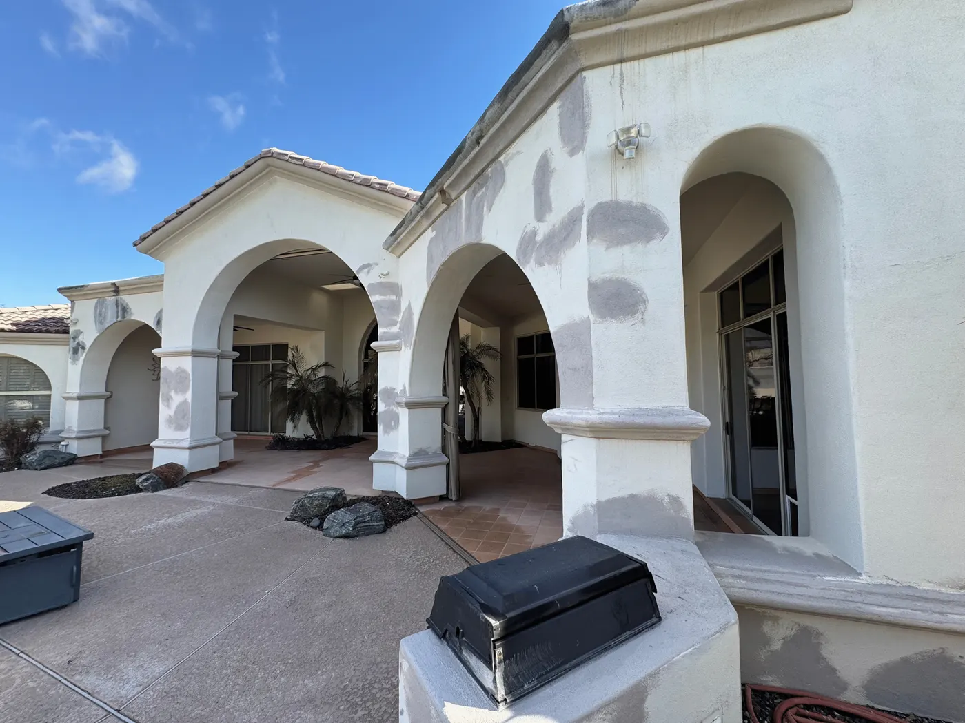 Stucco patch repairs primed on courtyard arches before repainting